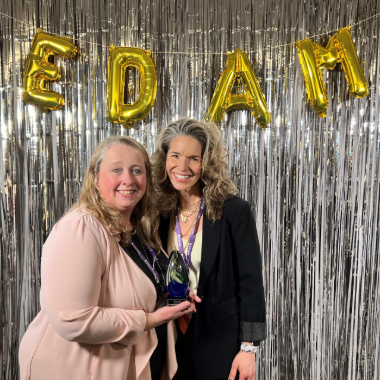 Stephanie holding award with Deanna in front of EDAM balloons and streamers