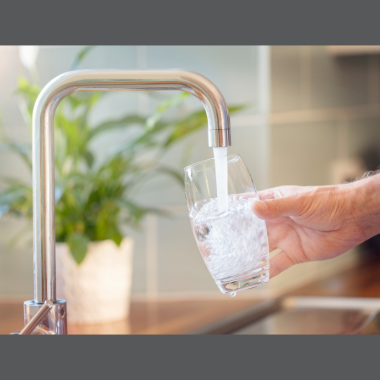 A faucet  in a kitchen sink filling a glass with water